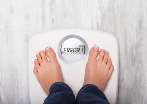 Woman standing on weight scale showing error message